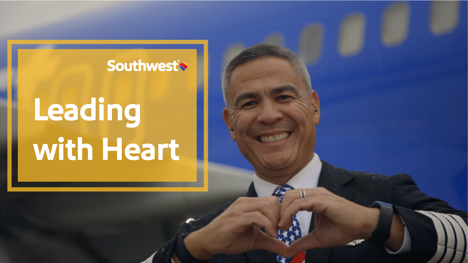 Captain Ernie M. holding up a Heart in front of a Southwest aircraft