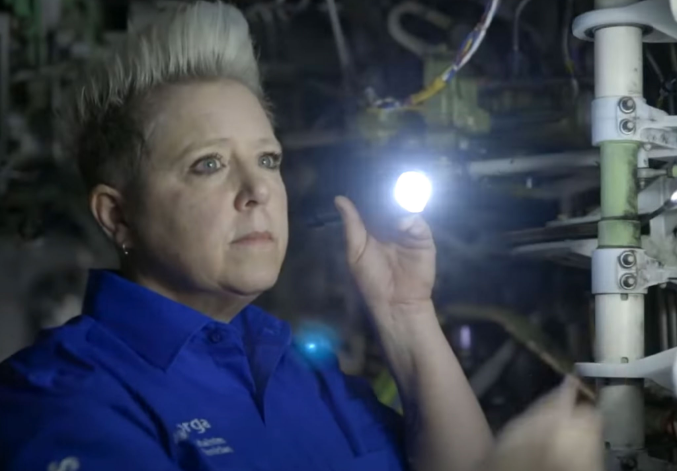 Photo of Jen M. holding a flashlight and inspecting the aircraft
