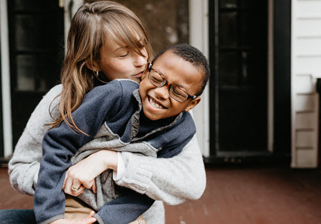 Mother hugging and kissing her child on the front porch
