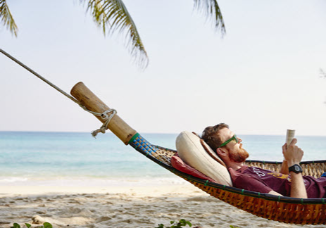 Man in a hammock reading a book on the beach
