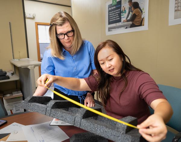 Two women measuring and working with custom packaging